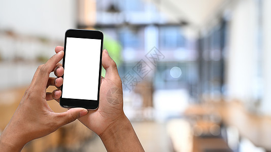 手持智能手机的咖啡馆背景模糊的人 空屏幕用于图形显示蒙太奇   info whatsthis图片