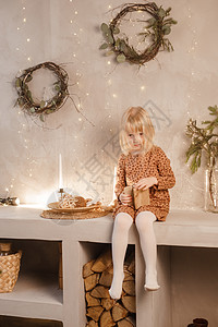 一个女孩在圣诞节前夕在一个为新年节日装饰的美丽房子里玩耍 斯堪的纳维亚式的内地有活林树和木质楼梯裙子孩子拥抱脚步圣诞礼物幸福客厅图片