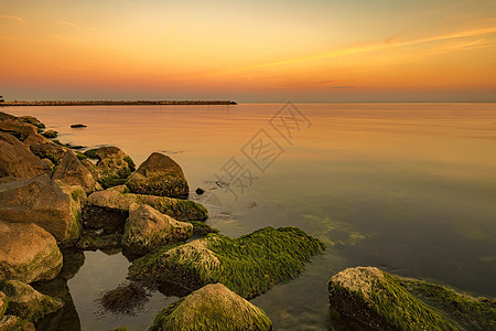 岩石上温暖的颜色和多彩的苔榈 海水在热辣的日落中振奋人心 海浪平滑地长期照射着图片