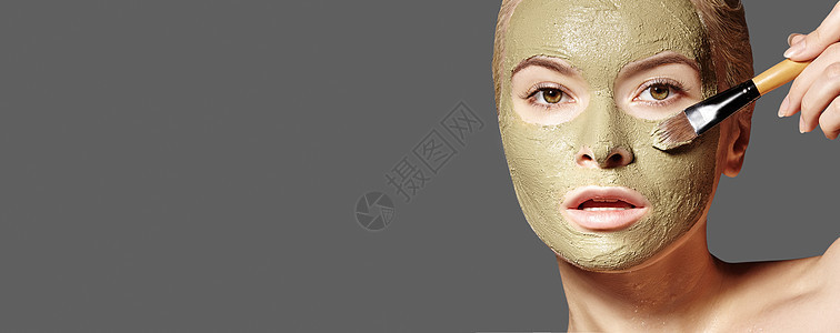 应用绿色面膜的美丽女人 美容护理 Spa 女孩在灰色背景上应用粘土面膜粉刺温泉剥离治疗面具女士说谎清洁福利身体图片