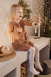 一个女孩在圣诞节前夕在一个为新年节日装饰的美丽房子里玩耍 斯堪的纳维亚式的内地有活林树和木质楼梯脚步工艺寒假礼物金发女郎饰品幸福图片