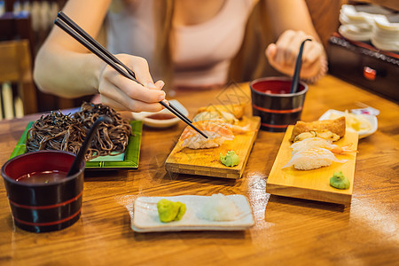 在咖啡馆吃寿司的年轻女人工作室美食女孩海鲜女士筷子餐厅饮食午餐嘴唇图片