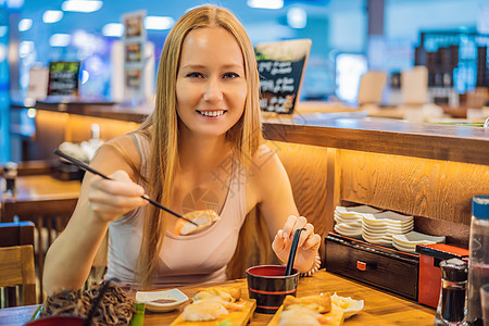 在咖啡馆吃寿司的年轻女人头发女性女士女孩筷子用餐美食海鲜盘子餐厅图片