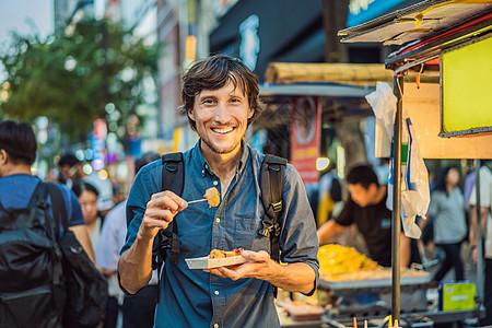 观光青年在汉城一条步行街上吃典型韩国街头食物的年轻人 在韩国Soul Korean当地马特克生活文化旅行男人快乐街道烹饪摊位民众图片