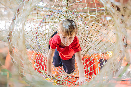 男孩在障碍课程中爬到网上电缆喜悦高架挑战乐趣训练营活动闲暇快乐运动员图片
