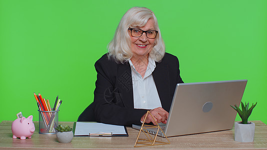 微笑成熟的成年商业妇女坐在工作场所办公服务台 开设笔记本电脑 开始工作成功学习退休企业家祖母女士老年网上购物金融色度图片
