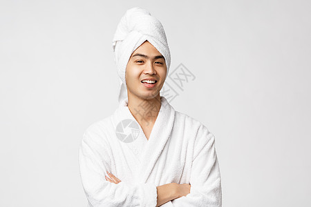 美容 水疗和休闲概念 英俊风趣的亚洲男人在家放松的画像 让自己舒服地头戴浴袍和浴巾 微笑着高兴 白色背景闲暇相机护理男性喜悦淋浴图片