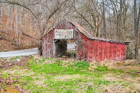 冬季末被废弃的红谷仓 涂有淡色油漆和旧牌子图片