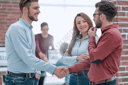 微笑的商务人士与当值同事握手相提并论办公室企业合伙项目男性商业职员会议专业成功图片