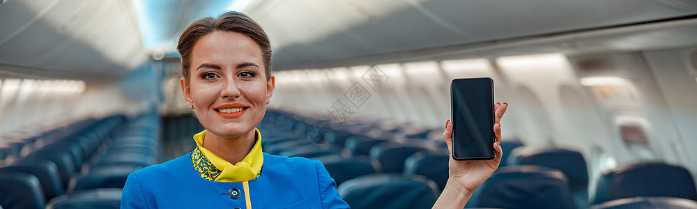 机舱里站着智能手机的快乐空姐女性技术电话航班座位喷射旅行客机航空公司空气图片