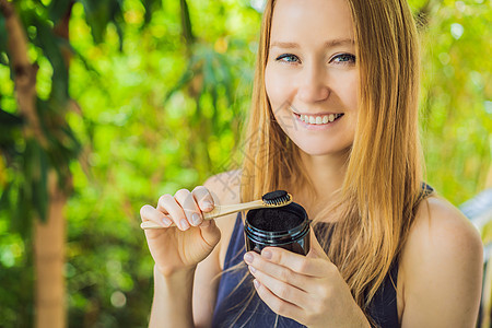 年轻女性使用活性炭粉刷牙刷牙和美白牙齿 竹生态刷粒子刮胡子卫生牙线排毒黄油椰子刷子健康吸水性图片