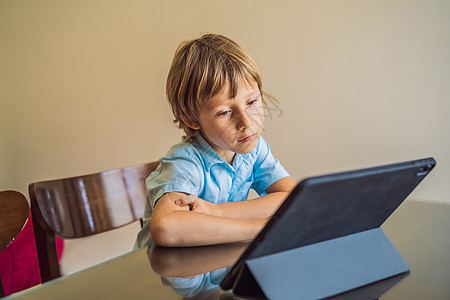 男孩使用平板电脑在家网上学习 在隔离期间学习 全球大流行共生19病毒消毒剂笔记本家庭作业面具教育男生阅读学校药片父亲图片