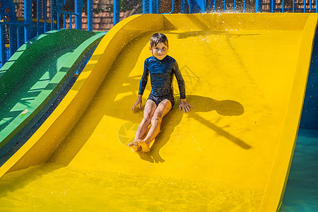 微笑的年轻男孩骑着黄色滑水滑行喜悦蓝色水槽水池男生娱乐幸福女孩活动童年图片