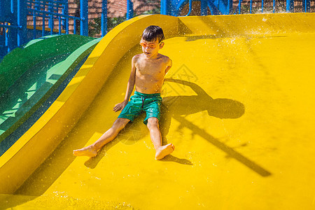 微笑的年轻男孩骑着黄色滑水滑行滑梯假期喜悦享受乐园活动女孩情感男人闲暇图片