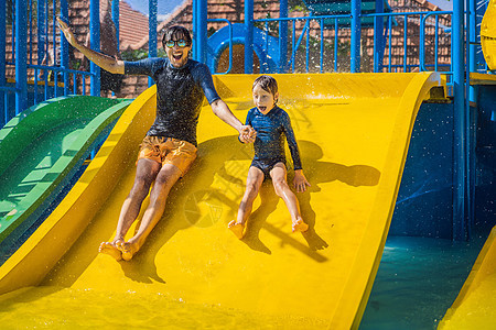 父亲和儿子在水中公园的水滑梯上戒指娱乐快乐孩子男性水池泳装旅行女孩速度图片