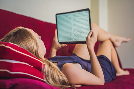 年轻女人在家沙发上看电子书女孩女士成人技术阅读读者互联网海滩电脑旅行图片