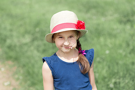 穿着草帽的小女孩 站在绿色草地上图片