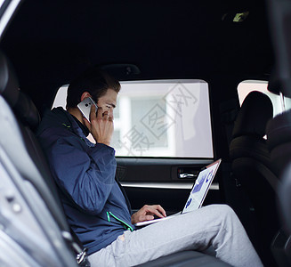 男商务人士在汽车里使用笔记本电脑和移动电话奢华商务男性管理人员车辆乘客套装旅行技术人士图片