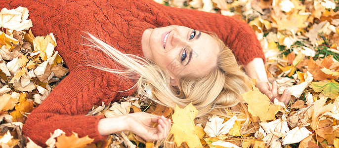 女人躺在黄色的叶子上背景女性季节幸福枫树享受微笑黑发快乐眼睛图片