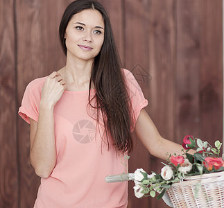 一位年轻女子的画像 她用自行车和篮子里的春花生活玫瑰喜悦女士女性黑发假期闲暇季节花束图片