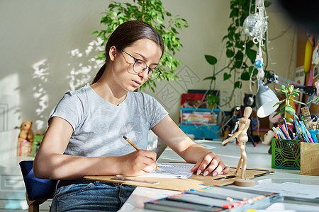 年轻有创意的女艺术家用铅笔画画 坐在家里的桌子上学生青年女性家庭作业乐趣爱好艺术家教育闲暇青少年图片