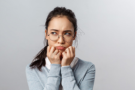 阴郁的被冒犯的年轻愚蠢的亚洲女人的特写镜头 皱着眉头生气 看起来带着嫉妒或遗憾 有难过的感觉 不公平的情况侮辱发生在她身上 站在图片