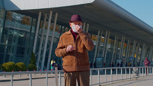 身戴保护面罩的老年养恤金领取者高级旅游祖父 避免机场附近出现冠状病毒预防爷爷乘客行李疾病假期封锁都市旅行感染图片