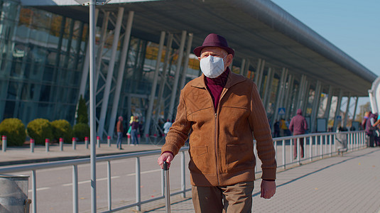 身戴保护面罩的老年养恤金领取者高级旅游祖父 避免机场附近出现冠状病毒预防旅行人士铁路运输封锁感染疾病药品行李图片