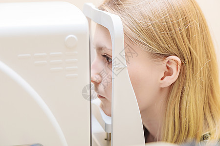 在眼科医生接待处的一个年轻女孩 检查她对一个特殊仪器的视力 近距离观察药品眼睛护理技术乐器视网膜电脑显示器医护人员诊所角膜图片