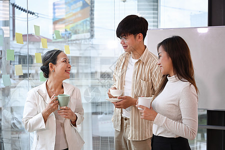 友好的行政商业领袖在办公室的咖啡休息时间与年轻员工讨论图片