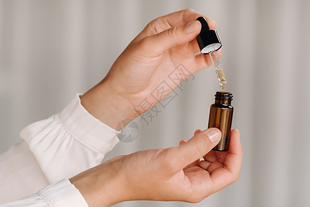 握着一瓶基本油水的近身女性手 阿罗玛疗法按摩师保健芳疗师按摩香水瓶子卫生治疗芳香女士图片