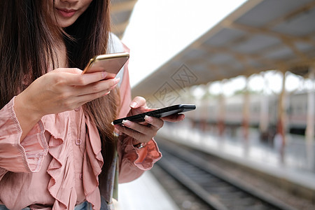 在火车站使用移动智能电话的女旅行者 旅行旅行旅费概念背包女士女性牛仔裤火车手机民众车站游客铁路图片