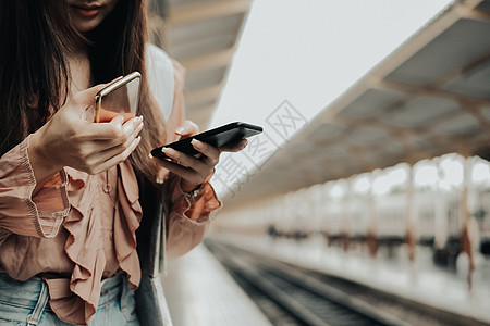 在火车站使用移动智能电话的女旅行者 旅行旅行旅费概念游客背包火车车站铁路运输牛仔裤女性女士平台图片