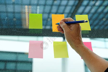 用手写在玻璃墙上的粘贴笔记上 粘滞笔记纸提醒讨论创意和商务集思广益的日程安排商业职场人士办公室女性窗户公司创造力女士邮政图片