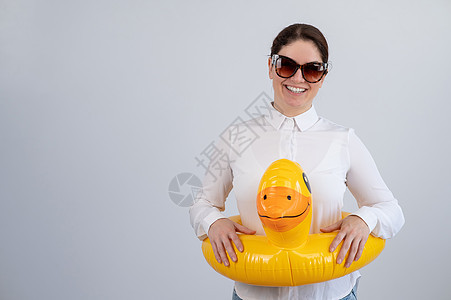 穿着白衬衫的白人女人 梦想着度假 戴着墨镜和可充气的鸭子浮标工作室假期橡皮衬衫游客游泳办公室休息喜悦图片