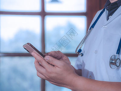 男医生使用智能电话查找信息 在医院里持有听诊器 保健和医学概念 和健康护理图片