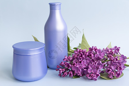 两瓶紫色罐子 配有化妆品产品和奶油 配有新鲜 盛开和香味的花朵雌蕊衬套香脂护理皮肤树叶花瓣保湿生物学治疗图片