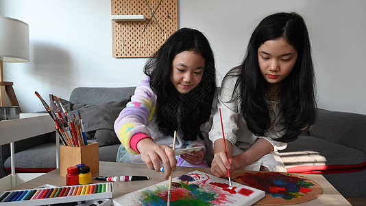 两个可爱的亚洲女孩在画布上画画 家里有油漆图片