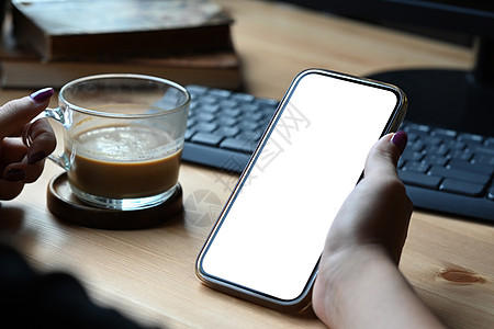 近距离观看女士拿着咖啡杯和假智能手机 为图形显示蒙迪奇提供空白屏幕图片