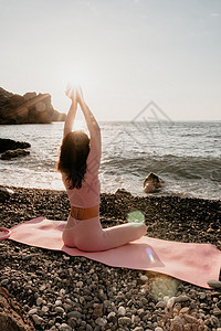 中年漂亮的女人 一头黑发 在卵石滩海边的瑜伽垫上用戒指做普拉提 女性健身瑜伽概念 健康的生活方式 和谐与冥想运动员平衡教程女孩讲图片