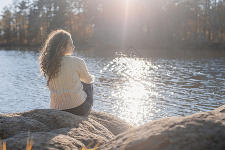 在秋天日落时 坐在河岸边的浪漫女人玻璃精神成人女性闲暇快乐太阳树木森林身体图片