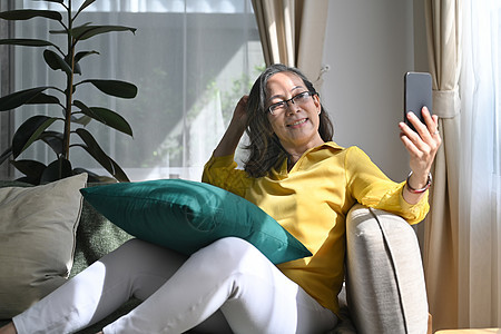 带着智能手机给朋友或亲戚打视频电话 享受愉快的谈话的快乐退休妇女 她们玩得开心图片
