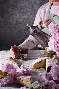 一位女性从银茶壶里倒茶 粉红樱花背景银壶香气杯子饮料阳台热饮液体微笑芳香活动图片
