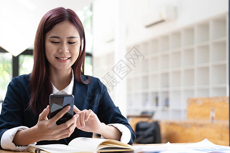 亚洲女性在电话里聊天 在带笑脸的笔记本电脑上工作 商务手机对话 在咖啡馆工作 咖啡馆生活方式 留在咖啡馆 新常态 学习 社交距离图片