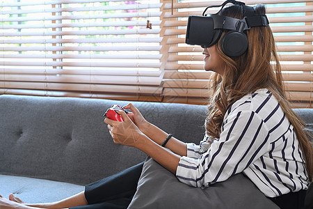快乐的年轻女子在家里拿着欢乐棒玩电子游戏 在虚拟现实听筒上播放视频游戏图片