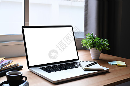 白色屏幕的笔记本电脑 木制桌上的咖啡杯广告工厂 家庭办公室工作场所概念图片