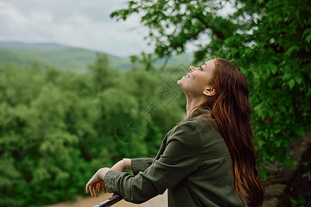 穿着雨衣的快乐女人 在春天走在春光中 在山河暴风雨附近的公园里情感季节女性全景享受森林天气下雨日落外套图片