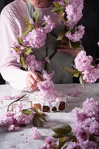 一个女人装饰自制复活节蛋糕 用粉红樱花和春花面包烹饪乡村假期女性母亲厨房房间庆典静物图片