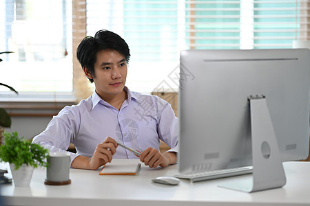 年轻的亚洲男性创业者在家庭办公室网上工作商人高清图片素材