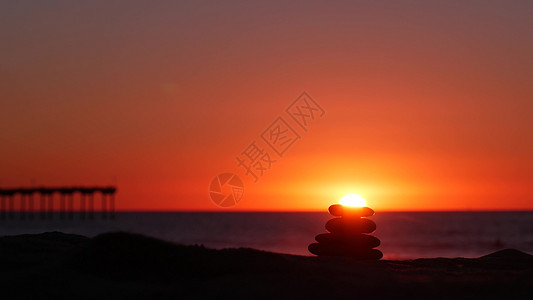 堆积着碎石 沙滩 日落的天空 岩石靠水平衡金字塔海洋燃烧支撑码头橙子波浪阳光气氛摄影图片